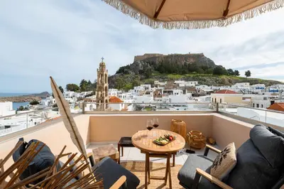 a balcony with a table and chairs and a view of the city at Tinas Lindian Serenity Villa in Líndos