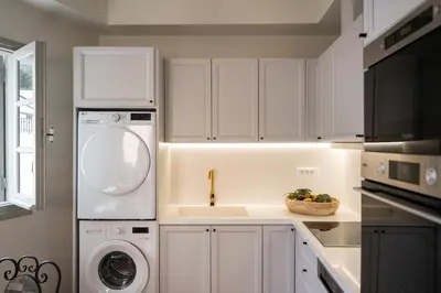 a kitchen with white cabinets and a washer and dryer at Tinas Lindian Serenity Villa in Líndos
