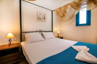 a bedroom with a large white bed with a blue blanket at Seascape Villa in Afantou