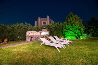 a row of white lounge chairs sitting on a lawn at night at Seascape Villa in Afantou