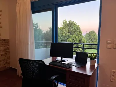 an office with a desk with a computer and a window at Seascape Villa in Afantou