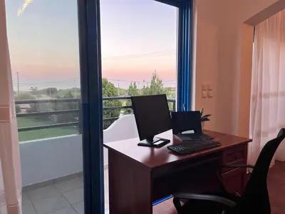 an office with a computer on a desk with a window at Seascape Villa in Afantou