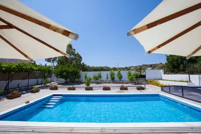 a swimming pool with two umbrellas and a pool at Villa Nefeli in Kiotari
