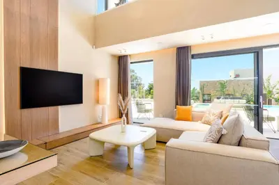 a living room with a couch and a tv at Villa Pefkos Cove by Villa Plus in Pefki Rhodes