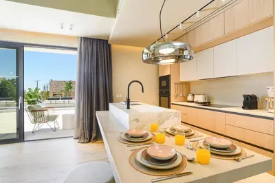 a kitchen with a table with plates and orange juice at Villa Pefkos Cove by Villa Plus in Pefki Rhodes