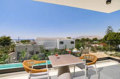 a table with two glasses of wine on a balcony at Villa Pefkos Shore by Villa Plus in Pefki Rhodes