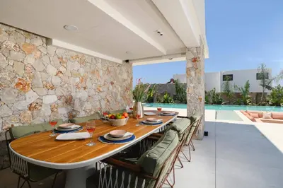 a dining room with a table and chairs and a pool at Villa Pefkos Shore by Villa Plus in Pefki Rhodes