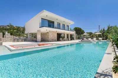 a villa with a swimming pool in front of a house at Villa Pefkos Shore by Villa Plus in Pefki Rhodes