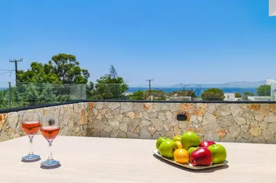 two glasses of wine and a plate of fruit on a table at Villa Pefkos Shore by Villa Plus in Pefki Rhodes