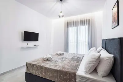 a white bedroom with a bed with white pillows at Ramo Luxury Villa in Kremasti