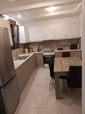 a kitchen with white cabinets and a table and a refrigerator at Damian House in Afantou