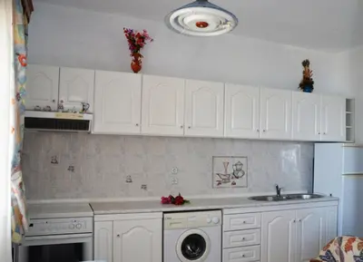a kitchen with white cabinets and a sink at Stegnailion in Archangelos