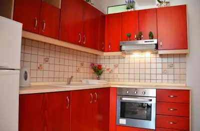 a kitchen with red cabinets and a sink and a stove at Stegnailion in Archangelos