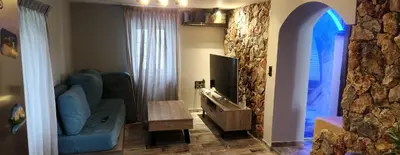 a living room with a blue couch and a tv at Oinos Luxury apartment in Faliraki
