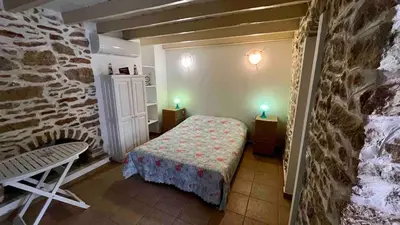 a small bedroom with a bed and a stone wall at La DESIRADE in Symi