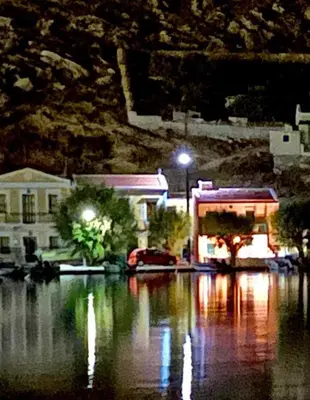 a city at night with a body of water at La DESIRADE in Symi