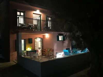 a house with chairs and a balcony at night at La DESIRADE in Symi