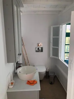a white bathroom with a sink and a toilet at La DESIRADE in Symi