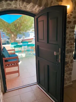 an open door leading to a patio with tables and chairs at La DESIRADE in Symi