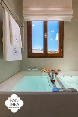 a bathroom with a bath tub with a window at Villa Panthea in Líndos