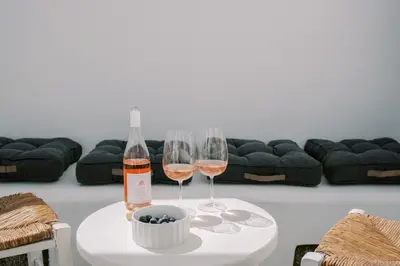 two wine glasses on a table with a bottle of wine at Aegean Nest in Koskinou