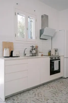 a white kitchen with white cabinets and a stove at Aegean Nest in Koskinou