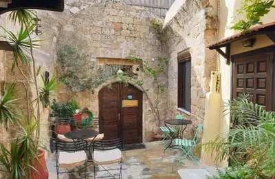 an outdoor patio with a wooden door and tables and chairs at Saint Michel Apartments in Rhodes Town
