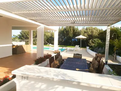 a patio with chairs and a table and a pool at Villa Chevalier in Kiotari