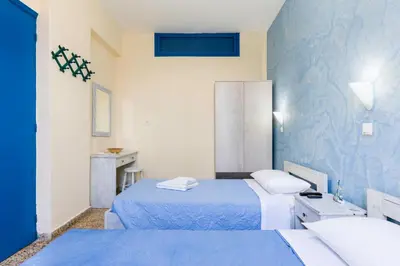 a bedroom with two beds and a blue wall at Vassos Apartments in Líndos