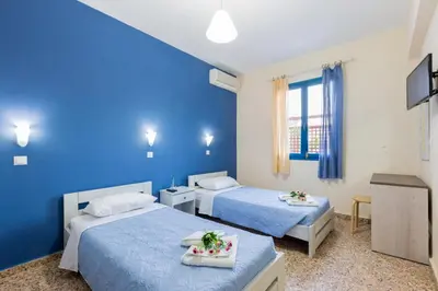 a bedroom with two beds and a blue wall at Vassos Apartments in Líndos