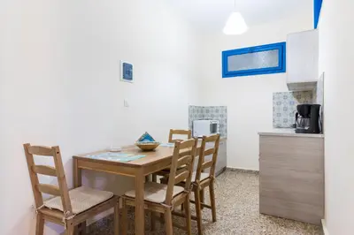 a kitchen with a wooden table and chairs in a room at Vassos Apartments in Líndos