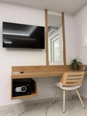 a room with a tv and a chair and a mirror at Harriet Beauty Studios in Haraki