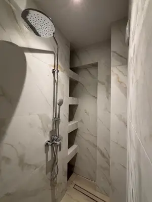 a shower in a bathroom with white marble walls at Harriet Beauty Studios in Haraki