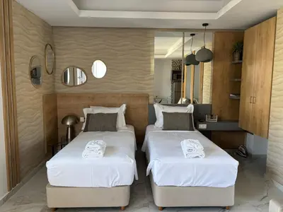 two beds in a small room with white sheets at Harriet Beauty Studios in Haraki