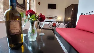 a bottle of wine and a vase with flowers on a table at Saint Michel Collection - Old Town in Rhodes Town