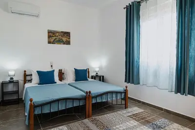 a bedroom with a bed with blue sheets and a window at Serenity Luxury Villa in Paradisi Rhodes in Rhodes Town