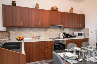 a kitchen with wooden cabinets and a table with plates and glasses at Serenity Luxury Villa in Paradisi Rhodes in Rhodes Town