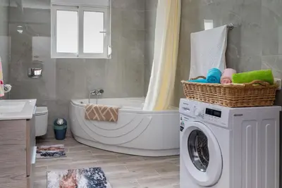 a bathroom with a tub and a washing machine at Serenity Luxury Villa in Paradisi Rhodes in Rhodes Town