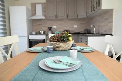 a kitchen with a table with plates and a basket of fruit at Myrteni guesthouse in Ialyssos
