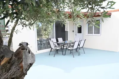 a patio with a table and chairs and a tree at Myrteni guesthouse in Ialyssos