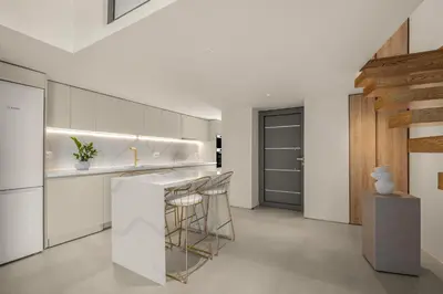 a kitchen with white cabinets and a bar with stools at Luxury in Simplicity , Nature's Touch , Mezzanine in Rhodes Town