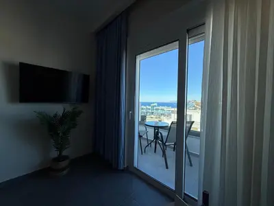 a room with a balcony with a table and a large window at Arfaras Home in Ixia