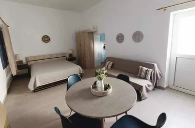 a living room with a table and chairs and a bed at La Stella studio in Livadia