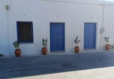three blue doors on a white building with potted plants at La Stella studio in Livadia