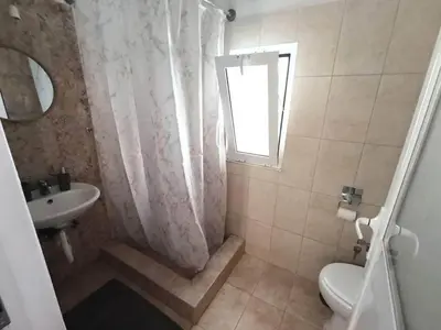 a bathroom with a sink and a toilet and a window at La Stella studio in Livadia