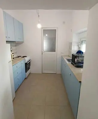 a white kitchen with blue cabinets and a door at La Stella studio in Livadia