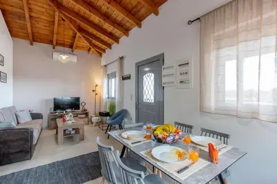 a dining room and living room with a table and chairs at Ampeli Villa in Kolimbia