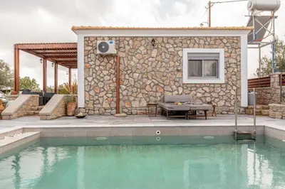 a house with a swimming pool in front of a building at Ampeli Villa in Kolimbia
