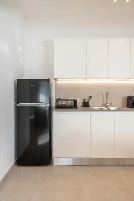 a kitchen with a black refrigerator and white cabinets at Spiti Apartment Ialysos in Ialyssos
