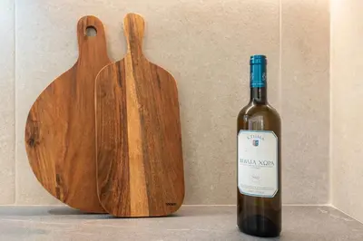 a bottle of wine next to a wooden cutting board at Spiti Apartment Ialysos in Ialyssos